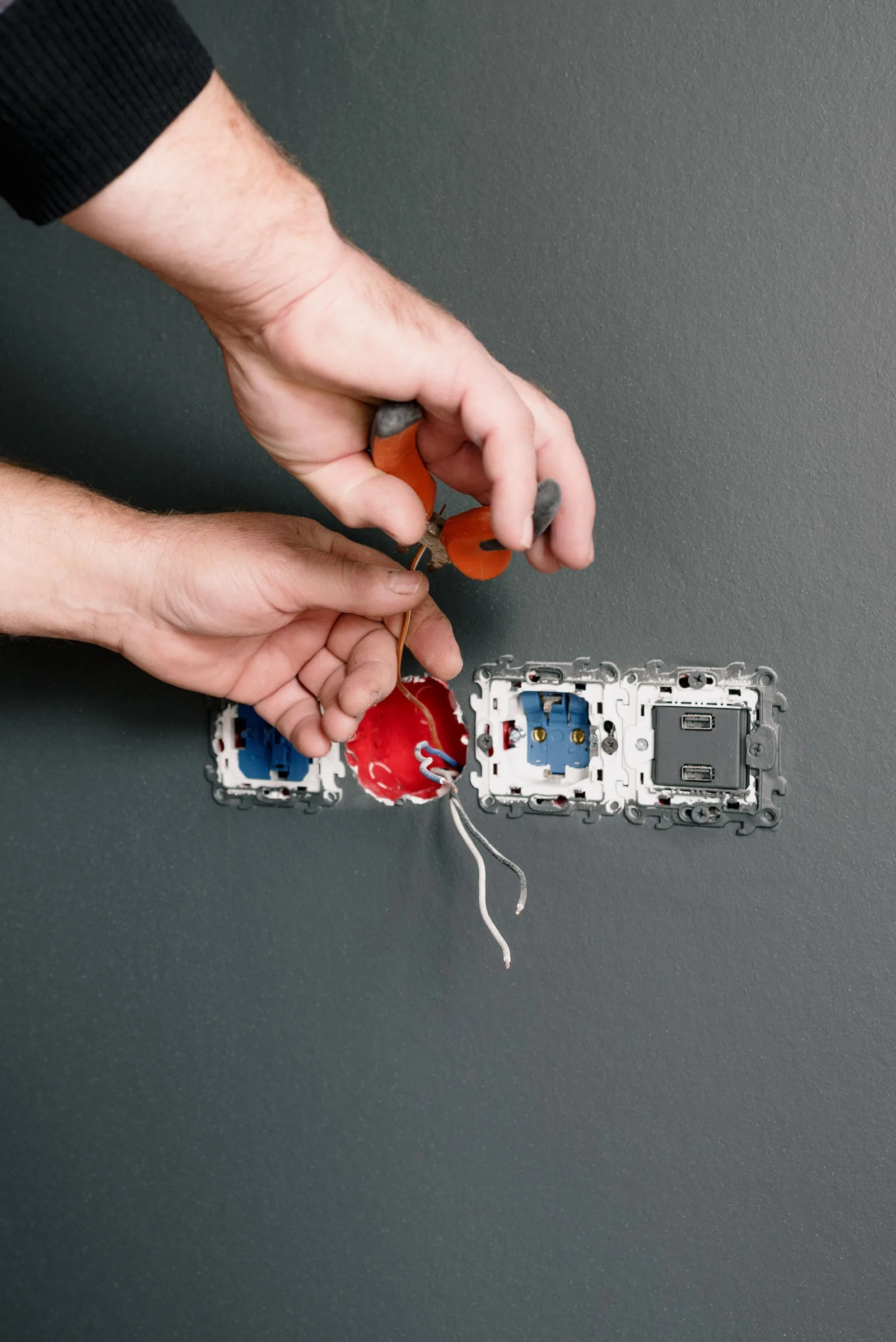 Technician terminating wiring at a wall outlet during cabling work